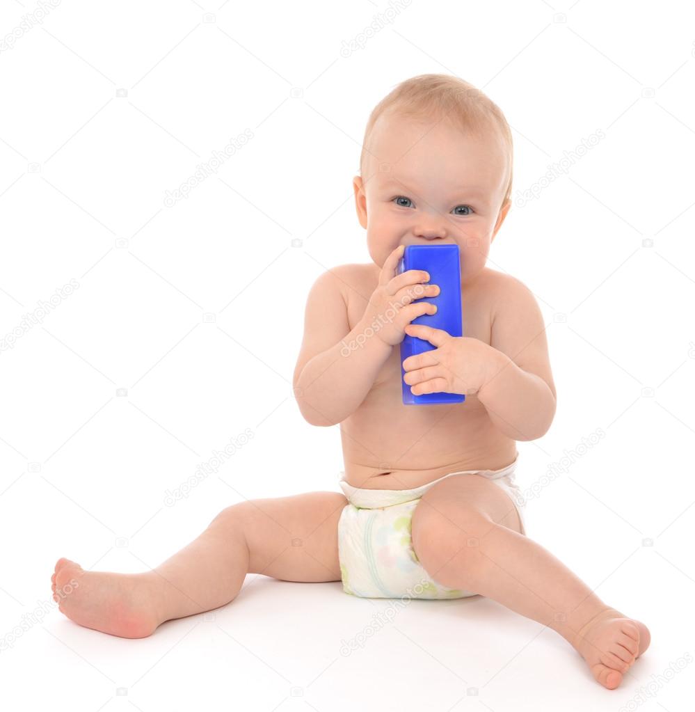 New born infant child eatind blue toy brick 