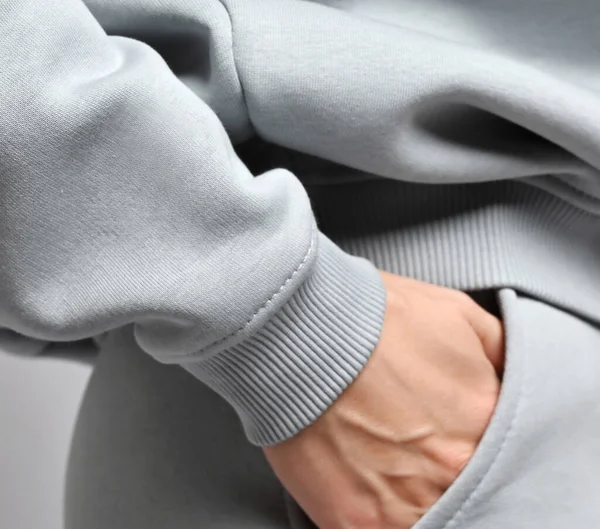 Acercamiento de la mujer fitness en traje deportivo gris sudadera con capucha y pantalones de pie de lado, cogida de la mano en su bolsillo Fotos de stock libres de derechos