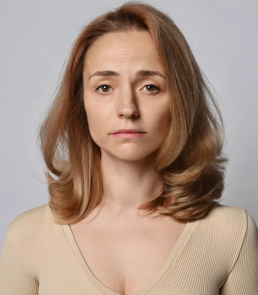 Retrato de jovem loira em camisa bege com mangas compridas olhando para a câmera sem sorrir — Fotografia de Stock