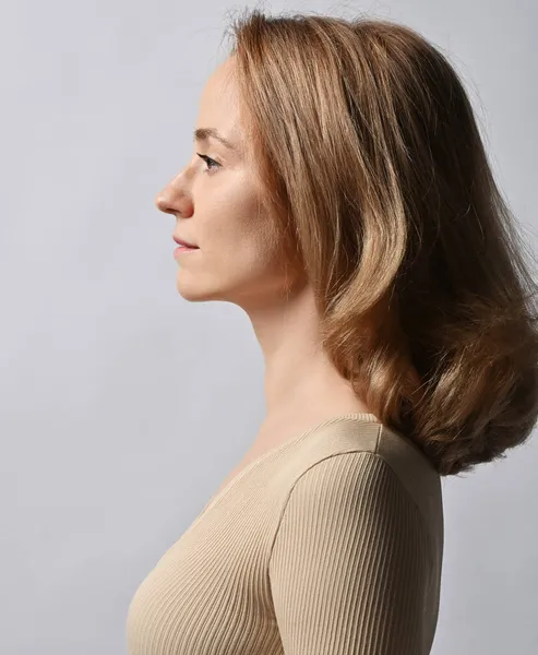 Portrait, profile of young woman in beige shirt with long sleeves and with long healthy silky blonde volumetric hair — Stock Photo, Image