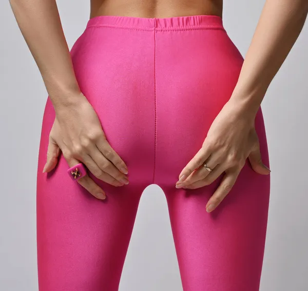 Closeup on slim woman buttocks and legs in pink leggings, holding sporty butt with hands, demonstrating dieting result — Fotografia de Stock