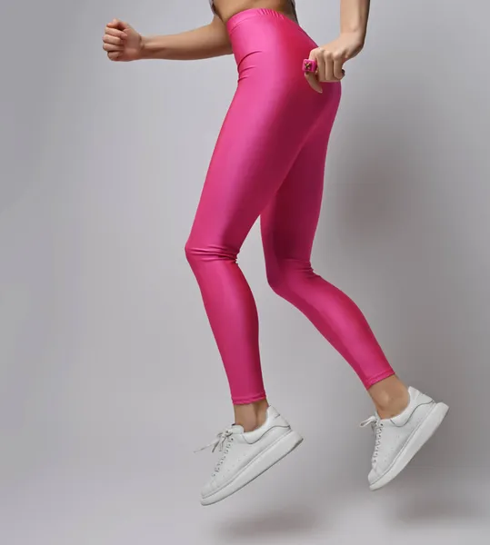 Primer plano de mujer delgada deportiva en leggings rosa y zapatillas blancas hace ejercicios deportivos, correr, trotar, saltar —  Fotos de Stock