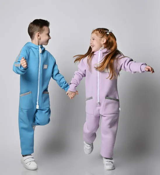 Παιδιάστικα παιδιά, αγόρια και κορίτσια με μπλε και ροζ φόρμες, τρέχουν μαζί κοιτώντας ο ένας τον άλλον. — Φωτογραφία Αρχείου