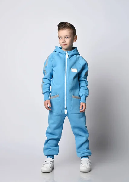 Ruhiger, smarter Junge im blauen Overall mit Reißverschluss und reflektierenden Streifen steht beiseite und schaut auf den Kopierraum — Stockfoto