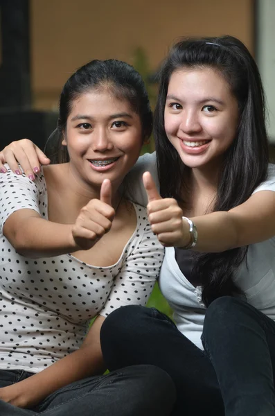 Две счастливые девушки позируют большими пальцами — стоковое фото