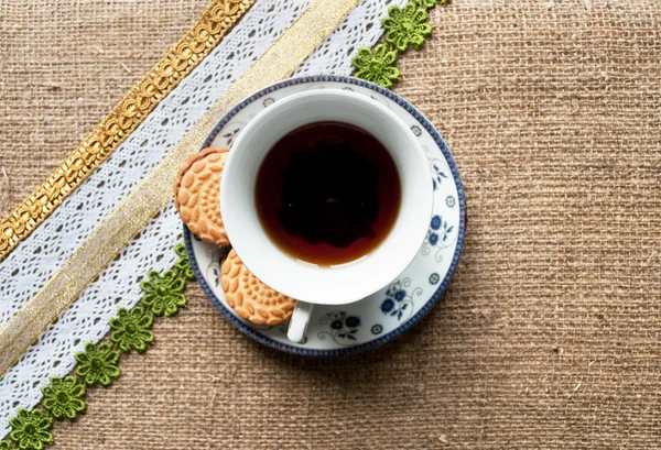 Köchinnen auf einem Teller mit einer Tasse Tee auf Tischdecke — Stockfoto