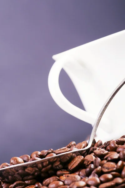 Koffiekopje omgeven door koffie bonen en scoop. — Stockfoto