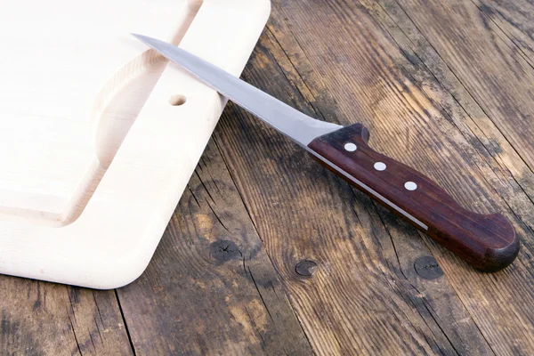 Cutting board and knife on old wooden table. — Stock Photo, Image