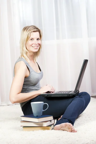 Mooie blonde vrouw in haar appartement via het internet. — Stockfoto