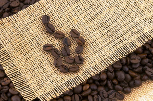 Med rostade kaffebönor på rustika tyg. — Stockfoto