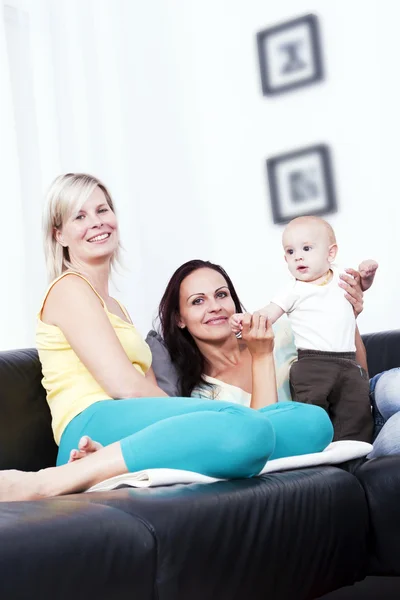 Mother and girlfriend in the living room of identical baby. — Stock Photo, Image