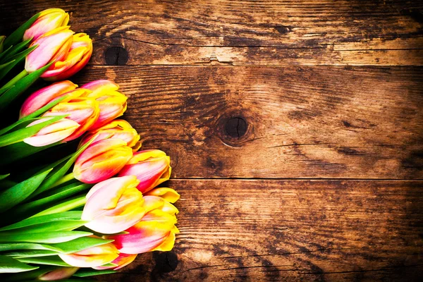 Schöne bunte Tulpen auf rustikalem Holzgrund. — Stockfoto