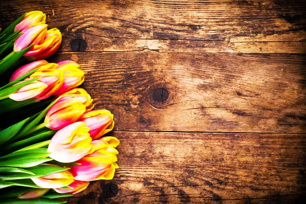 Tulipány ve staré dřevěné pozadí. — Stock fotografie