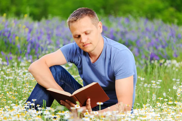 En man läser en bok i fältet. — Stockfoto