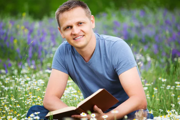 Muž čte knihu v poli. — Stock fotografie
