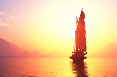 Renkli arka planda yelkenleri olan eski bir tekne.