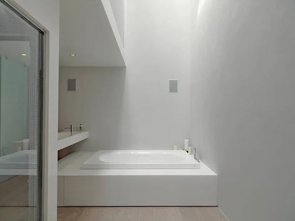 现代浴室的内部图片说明在浴室的前景后面是浴缸 后面是挂着的洗脸盆 而地板是木制的 — 图库照片