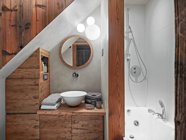 деревенский санузел, на переднем плане прилавок верхний умывальник на деревянном умывальнике и круглое зеркало, справа ванна