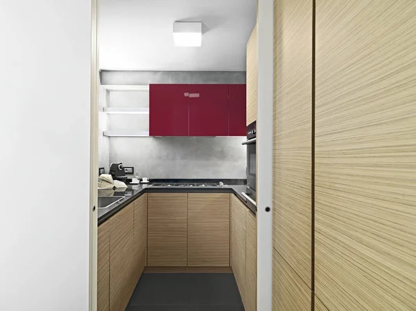 Kırmızı duvar üniteleri ve ahşap dolaplarla modern mutfak iç mimarisi.
