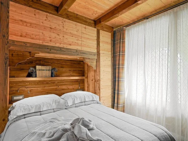 有木制壁炉架的乡村式卧房 右边有木制天花板 大窗户上有窗帘 — 图库照片