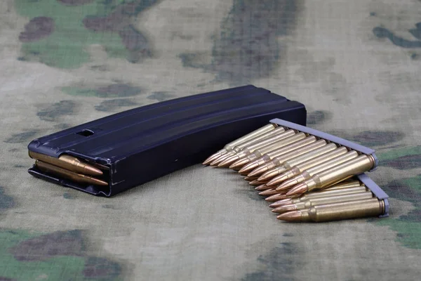 5.56mm ammunition with full metal jacket bullet with magazine on camouflage uniform background