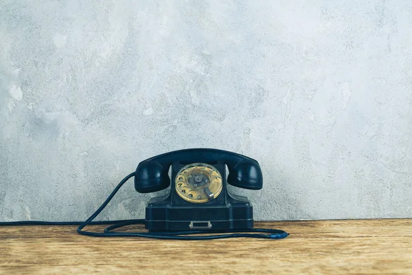 Ρετρό Μαύρο Περιστροφικό Τηλέφωνο Ξύλινο Τραπέζι Μπροστά Γκρι Φόντο Τσιμέντο — Φωτογραφία Αρχείου