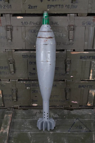 Soviet or russian 120 mm mortar shell on army green crate. Text in russian - type of ammunition, projectile caliber, projectile type, number of pieces and weight.