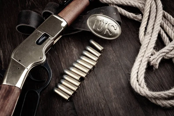 Old west gun - lever-action repeating rifle with cartidges and US marked US Army bronze buckle on wooden table