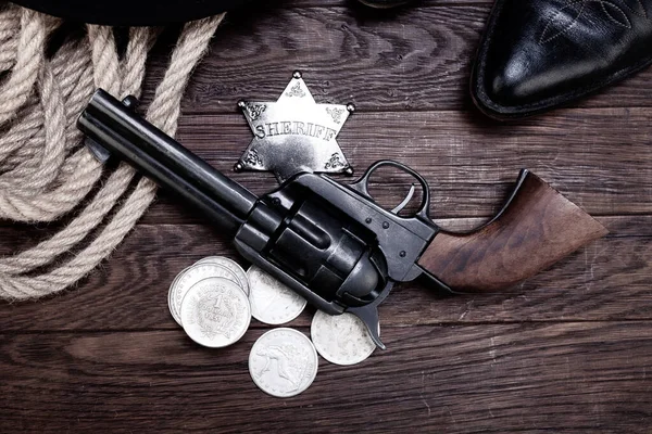 Old west law enforcement - revolver guns with sheriff badge and silver dollars with hat, rope and cowboy boots