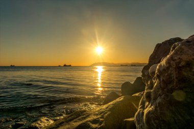 Karadeniz 'in kayalık sahillerinde gün batımı. Krasnodar Bölgesi Novorossiysk körfezi manzaralı. Güneş ışığıyla aydınlatılmış.