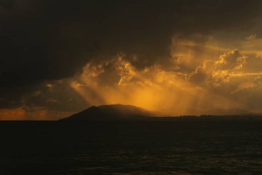 Kara bulutlar güneş ışınlarını delip geçiyor. Bir fırtına denize yaklaşıyor. Olumsuz bir kasırga.
