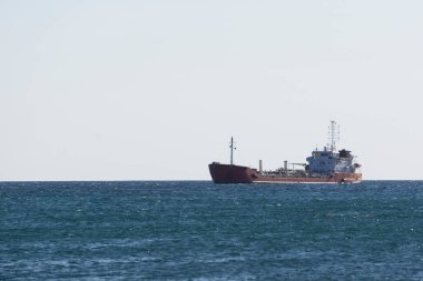 Denizdeki bir kargo gemisi, sıcak bir günde, ufukta, rotasında ilerliyor.