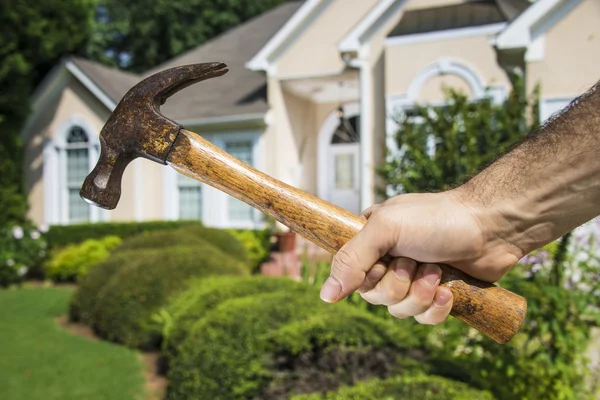 Hand met hamer in de voorkant van het huis — Stockfoto