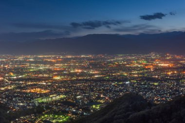 Kofu, Yamanashi, Japonya sehri alacakaranlıkta tepeden yükseliyor..