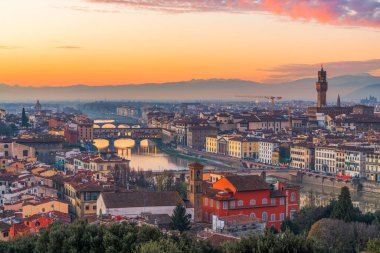 Florence, Italy cityscape overlooking the Ponte Vecchio Bridge crossing the Arno River at twilight.