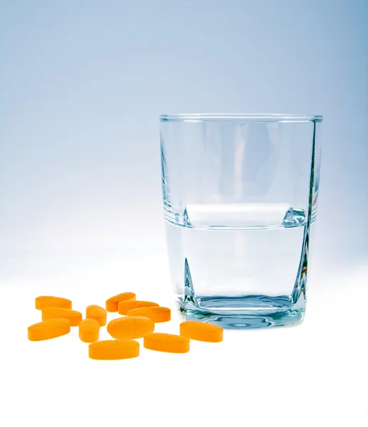 Vitaminen met glas water geïsoleerd — Stockfoto