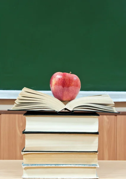 Maçã em uma pilha de livros em um contexto um conselho de escola — Fotografia de Stock