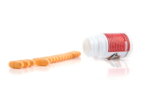 Vitaminen worden uitgestort in een rij van een kleine fles geïsoleerd — Stockfoto