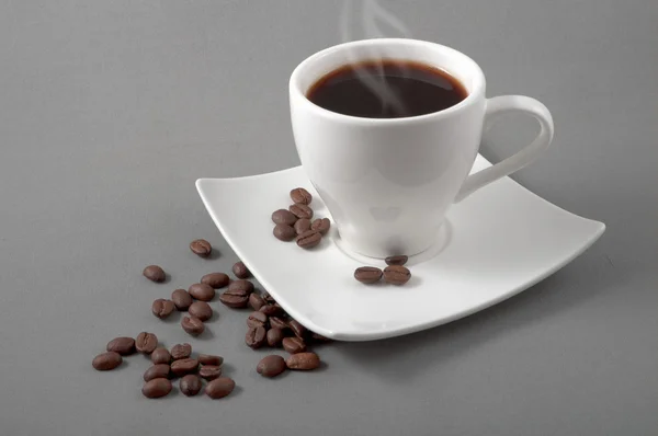 Coffee in grains is spilled on a saucer with a cup — Stock Photo, Image