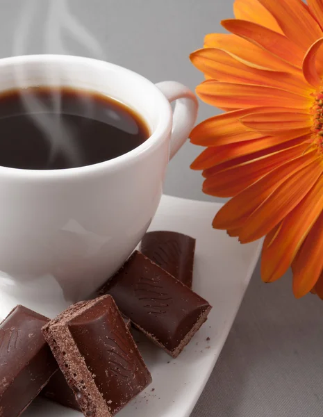 Черный кофе и шоколад на фоне оранжевого цветка — стоковое фото