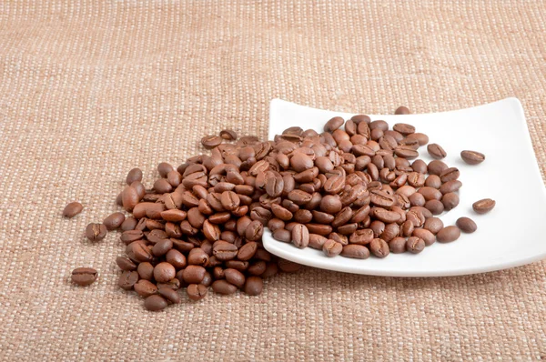 Зерно кофе в блюдце на мешок разбросаны — стоковое фото