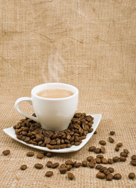 Coffee and milk and saucer with grains on a background sacking — Stock Photo, Image