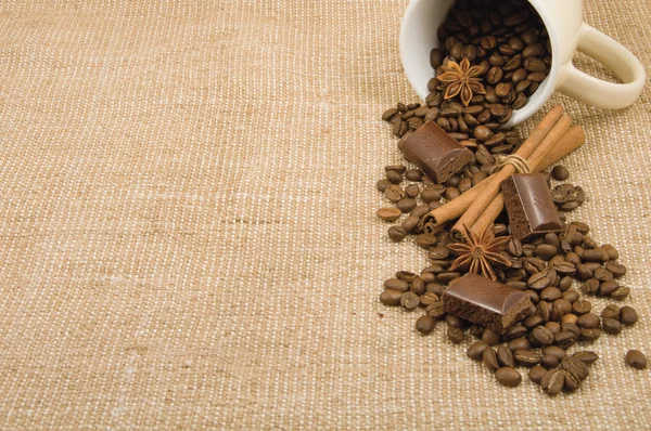 Coffee grain, cinnamon, chocolate and anise on a background sack — Stock Photo, Image