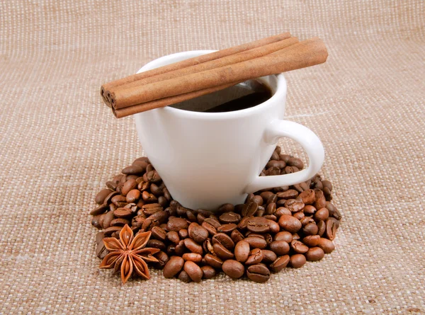 Cinnamon sticks are on a cup of black coffee in the surroundings — Stock Photo, Image