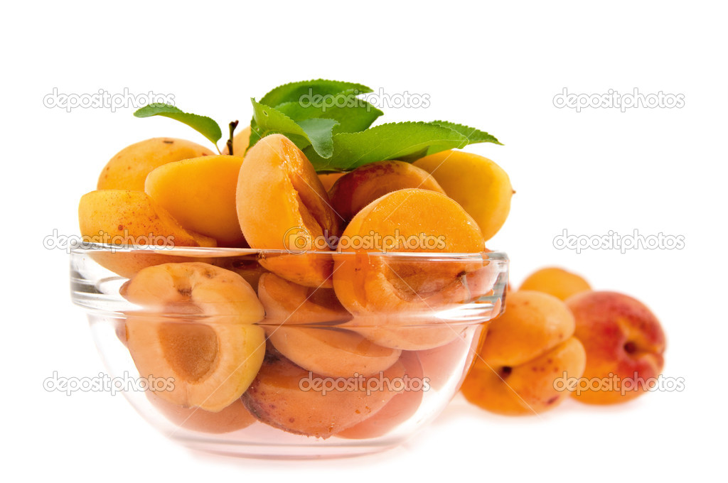 halves apricot in a dish on a background whole apricot