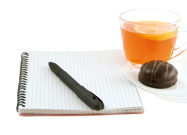 Cuaderno con bolígrafo y té con limón sobre fondo blanco — Foto de Stock
