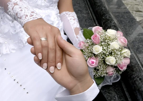 Een man houdt de hand van de vrouw op een achtergrond een boeket — Stockfoto