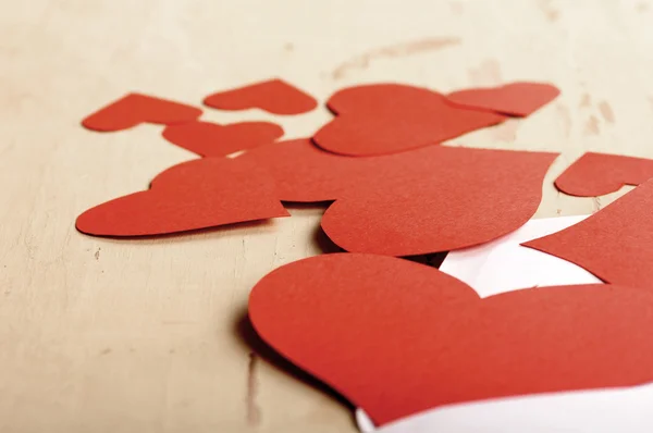 Hearts poured out from the envelope on the old yellow table — Stock Photo, Image