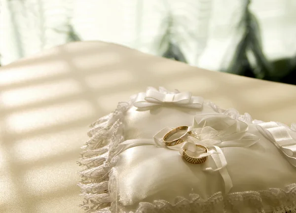gold wedding rings on a satin pillow