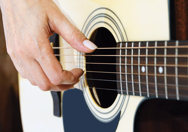 woman hand plucking strings on a guitar